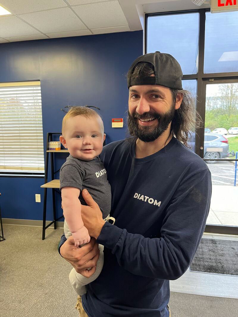 Robbie holds baby Preston. They smile for the camera while wearing their matching "Diatom" t-shirts!