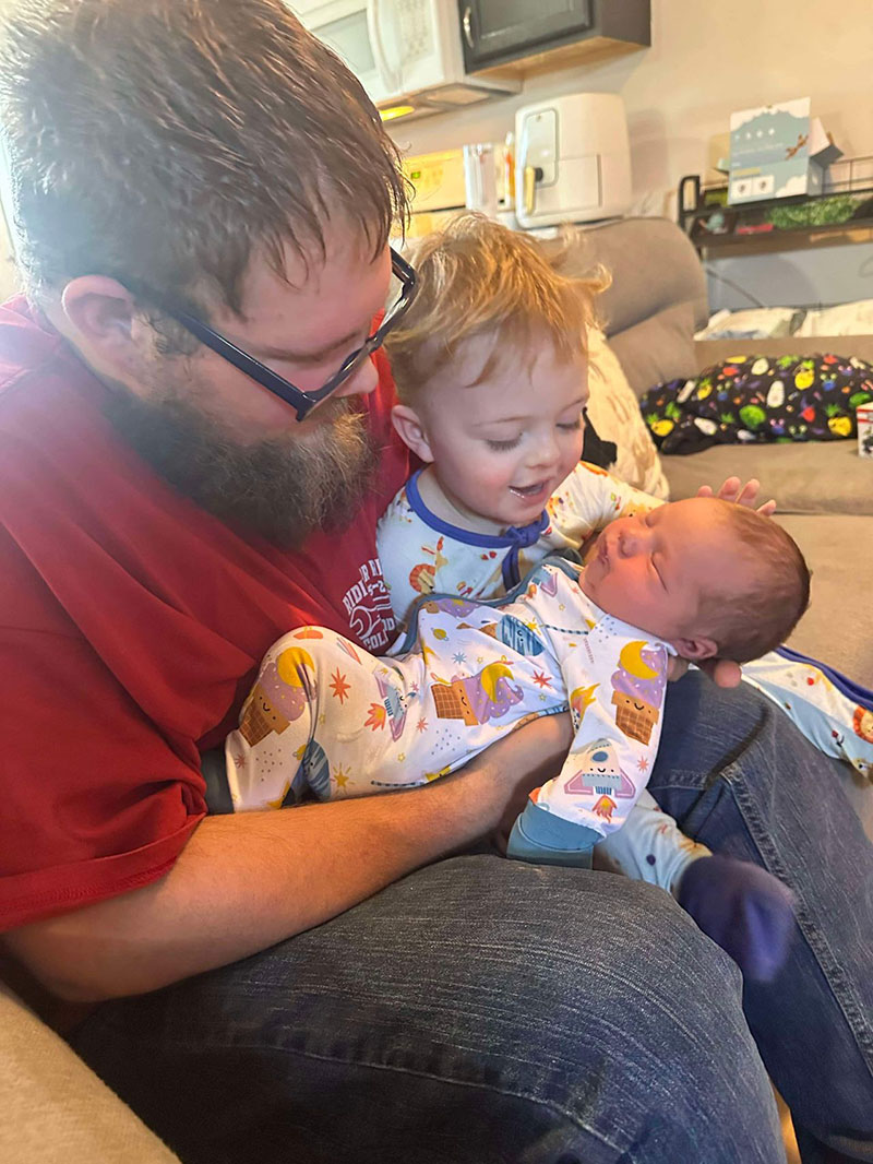 Skylar's son River sits on his dad's lap while Skylar holds baby LilyKate.